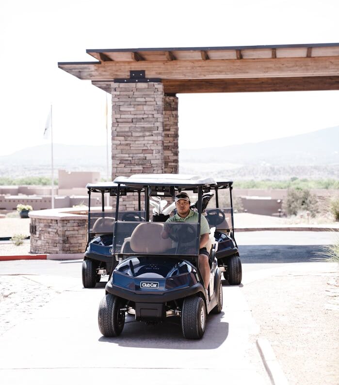 Man Wearing Grey Polo Shirt Riding Blue and White Golf Cart